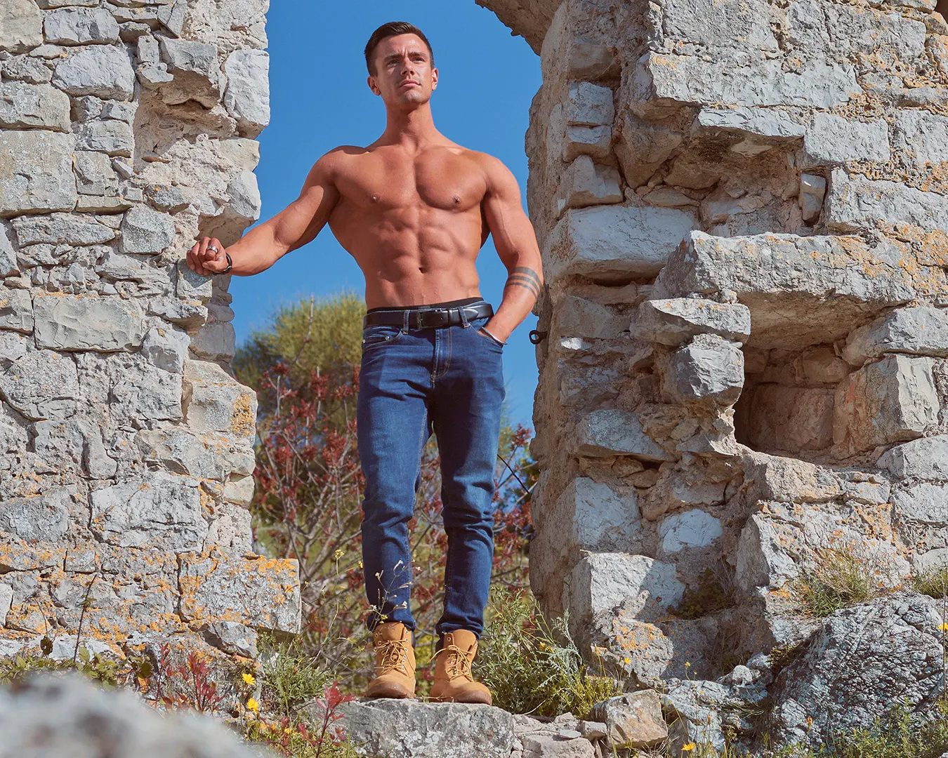 Athlète masculin torse nu et musclé posant dans des ruines de pierre, séance photo fitness en extérieur sur la Côte d’Azur