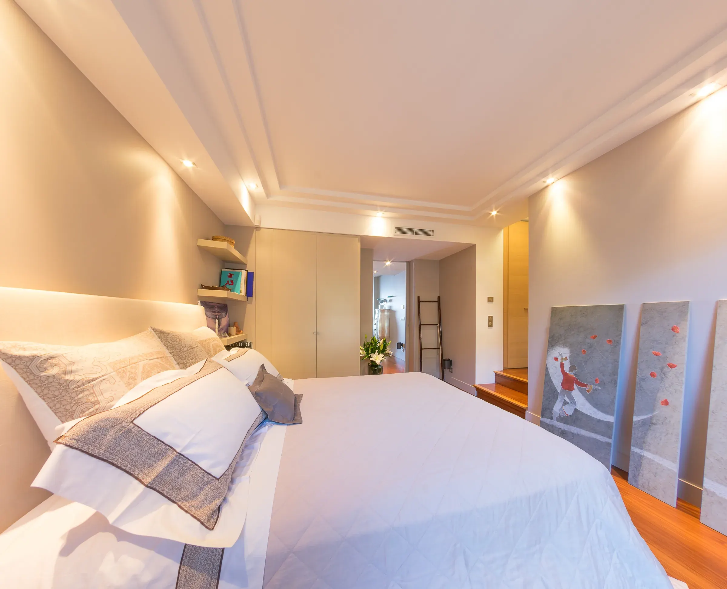 Chambre lumineuse au linge brodé, plafond à spots LED et toiles d'art, photographie immobilière Suisse romande & France