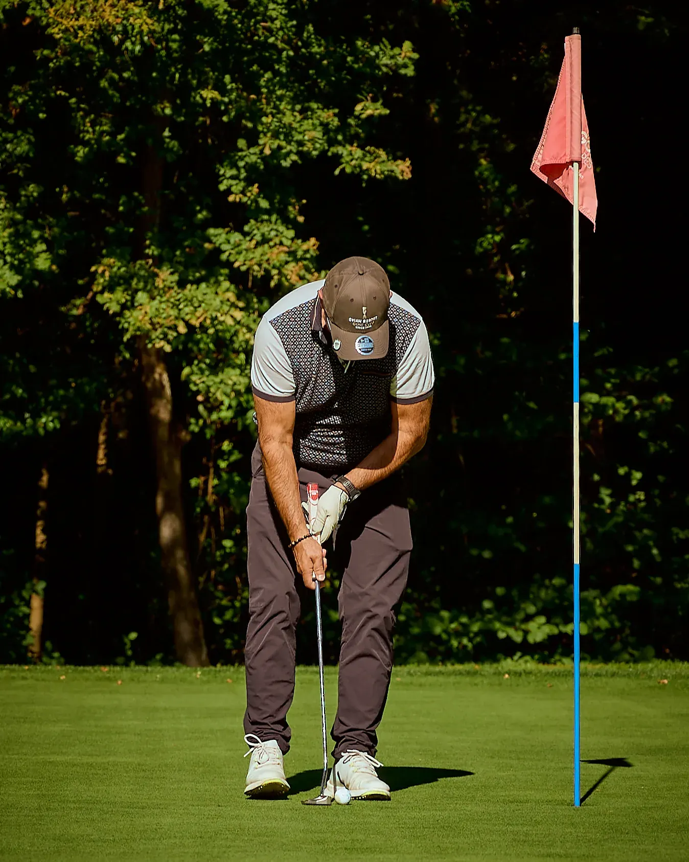 Golfeur concentré sur son putt près du drapeau rouge, green du Golf des Alpes à Giez, reportage photo événementiel