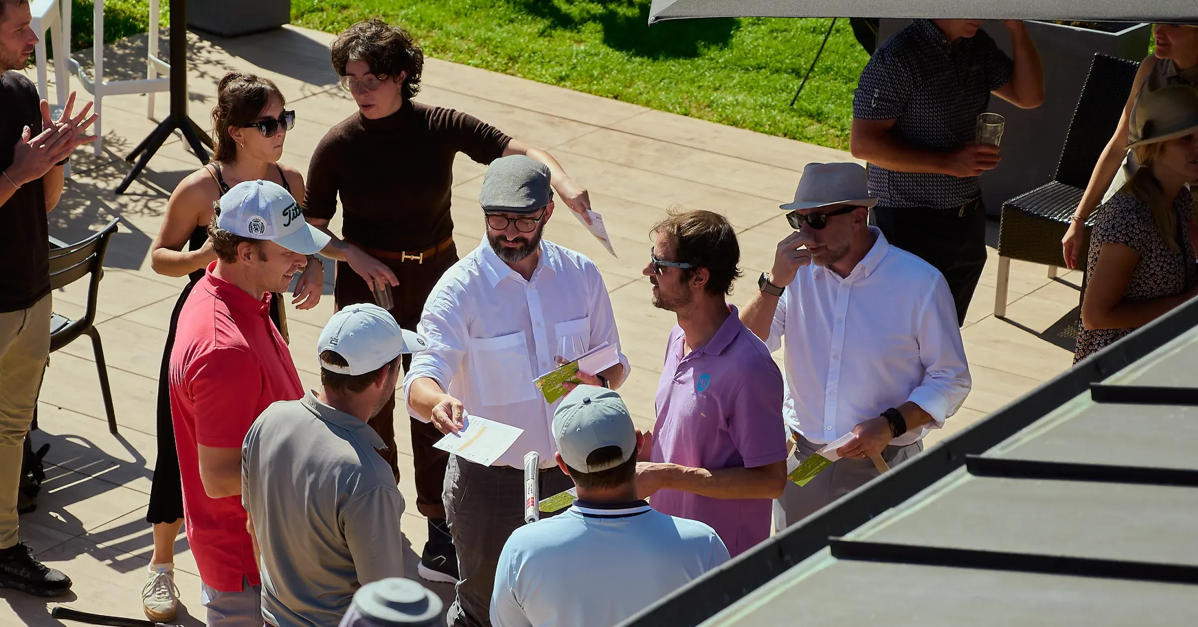Golfeurs réunis sur la terrasse du club-house à Giez, échangeant leurs cartes de score sous le soleil, reportage événementiel