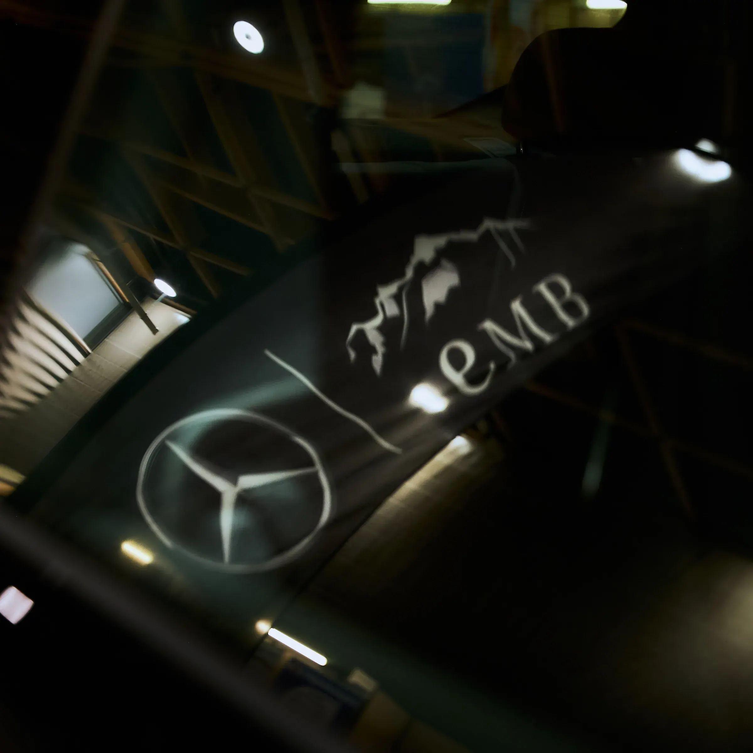 Étoile Mercedes-Benz et logo EMB projetés sur une carrosserie noire laquée, photographe automobile à La Roche-sur-Foron