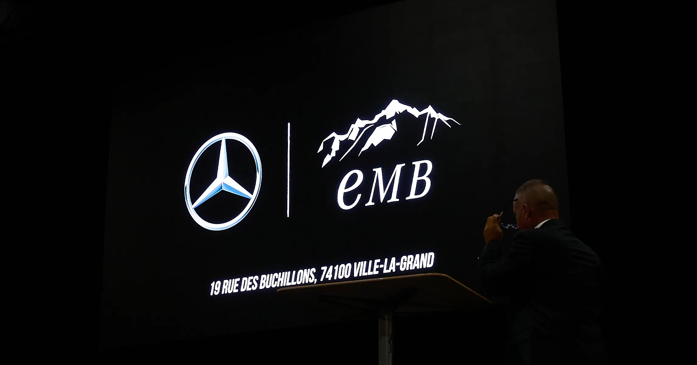 Logos Mercedes-Benz et EMB projetés sur scène, orateur au pupitre, reportage événementiel automobile à La Roche-sur-Foron
