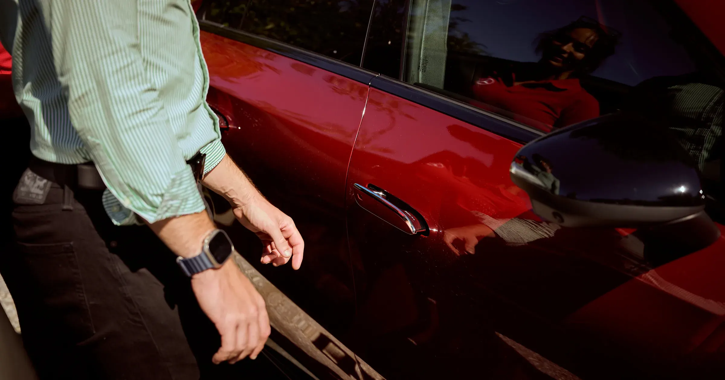 Main d'un homme effleurant la poignée chromée d'une Mercedes-Benz rouge, reflets sur la carrosserie, photographe automobile à Giez