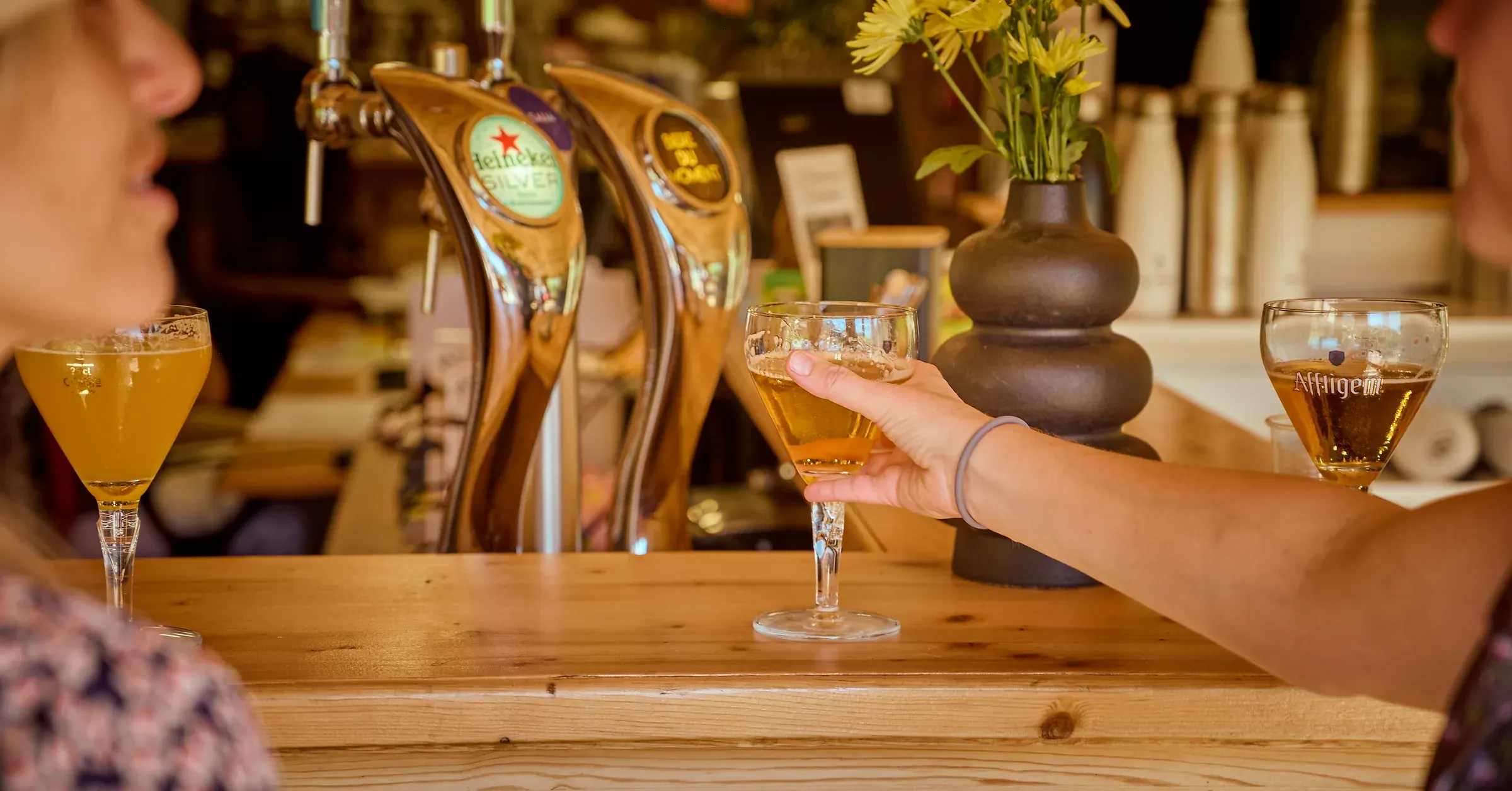 Main saisissant un verre de bière blonde sur le comptoir en bois du bar, Golf des Alpes à Giez, reportage photo d'événement