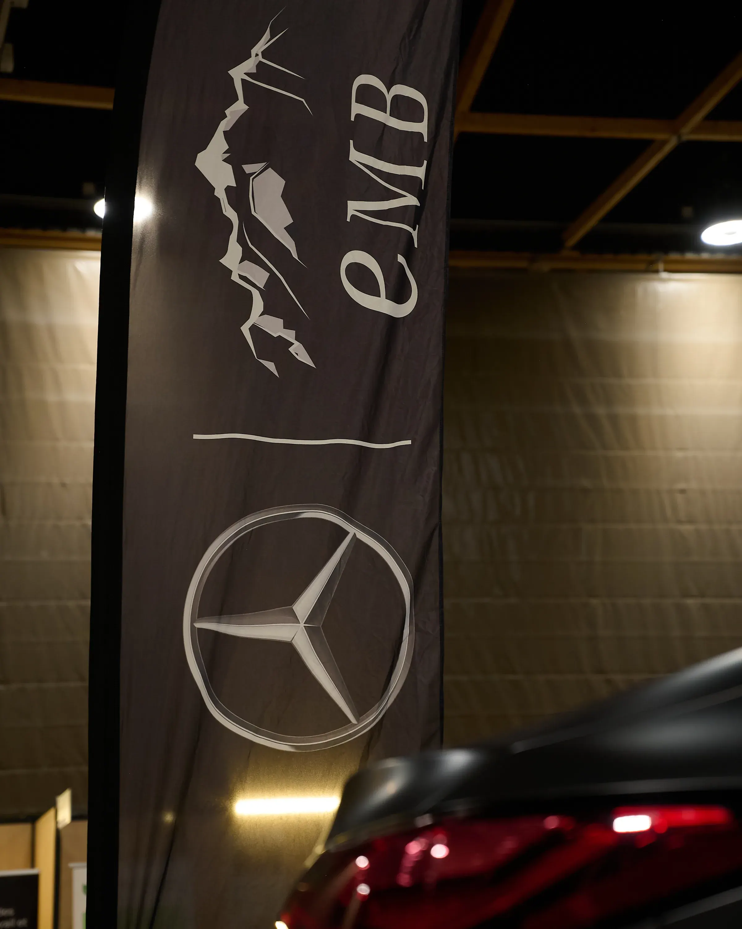 Oriflamme Mercedes-Benz et logo EMB au-dessus d'une berline noire aux feux rouges, photographe automobile à La Roche-sur-Foron