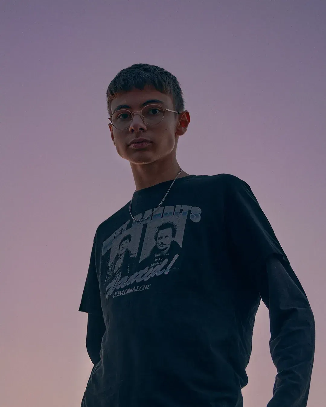Portrait d'un jeune homme à lunettes rondes en t-shirt noir, contre-plongée sur un ciel mauve au crépuscule, par un photographe portraitiste à Nice