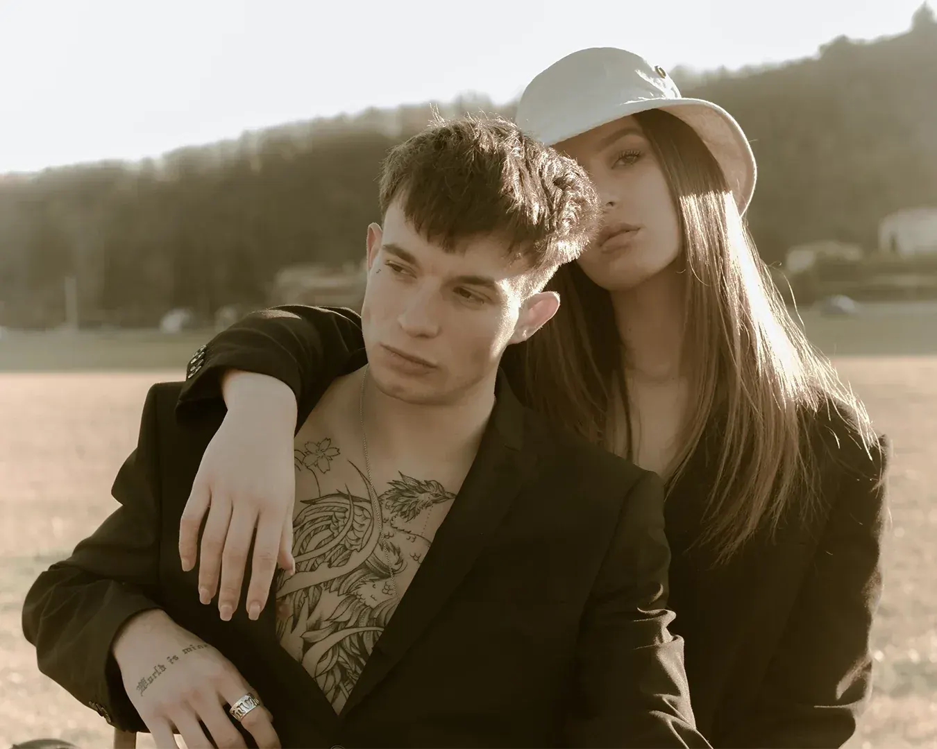Portrait de couple en lumière dorée, homme tatoué en veste noire et femme au bob blanc, photographe portraitiste à Nice