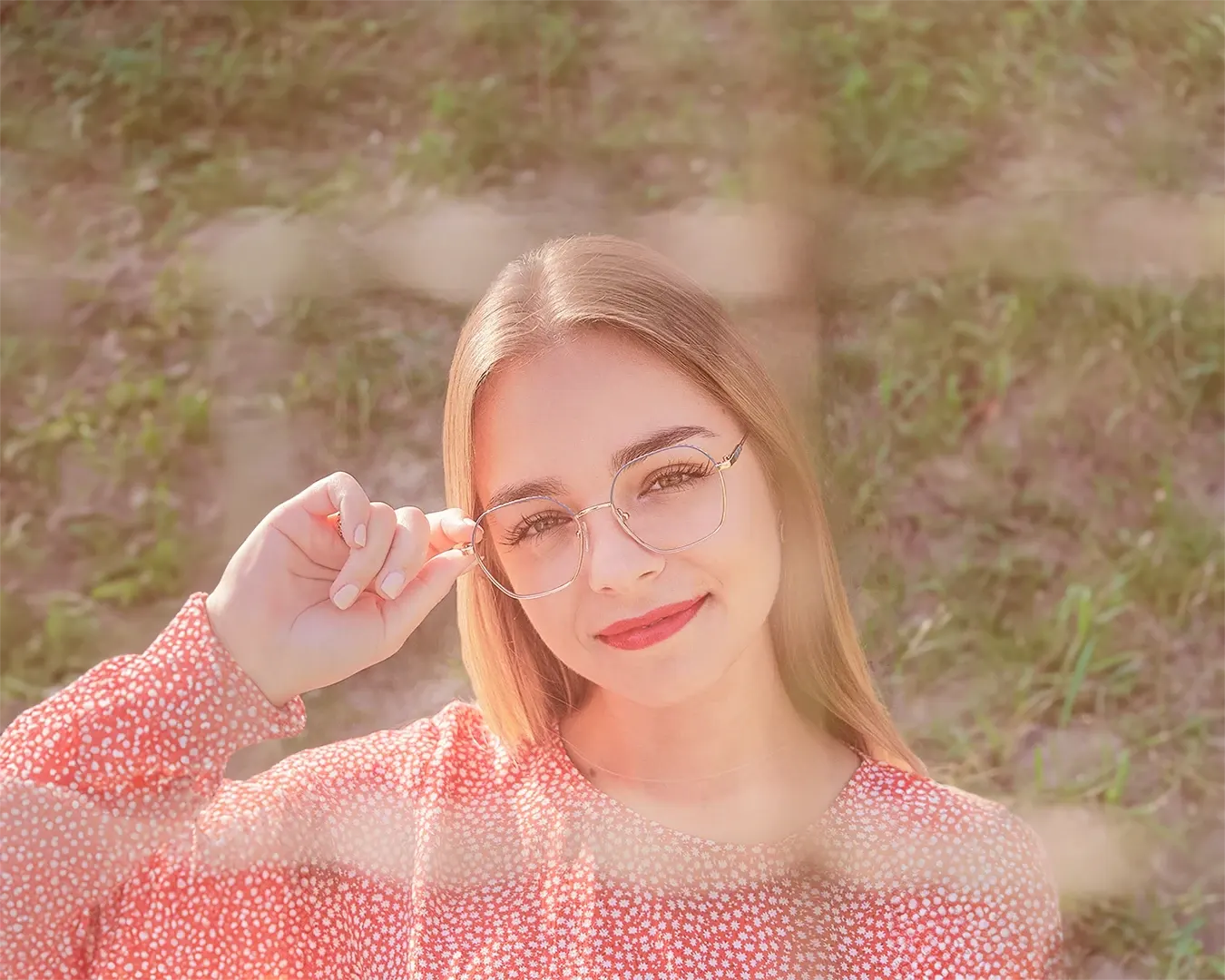 Portrait d'une jeune femme blonde aux lunettes dorées et en blouse corail, lumière dorée en extérieur, photographe portrait
