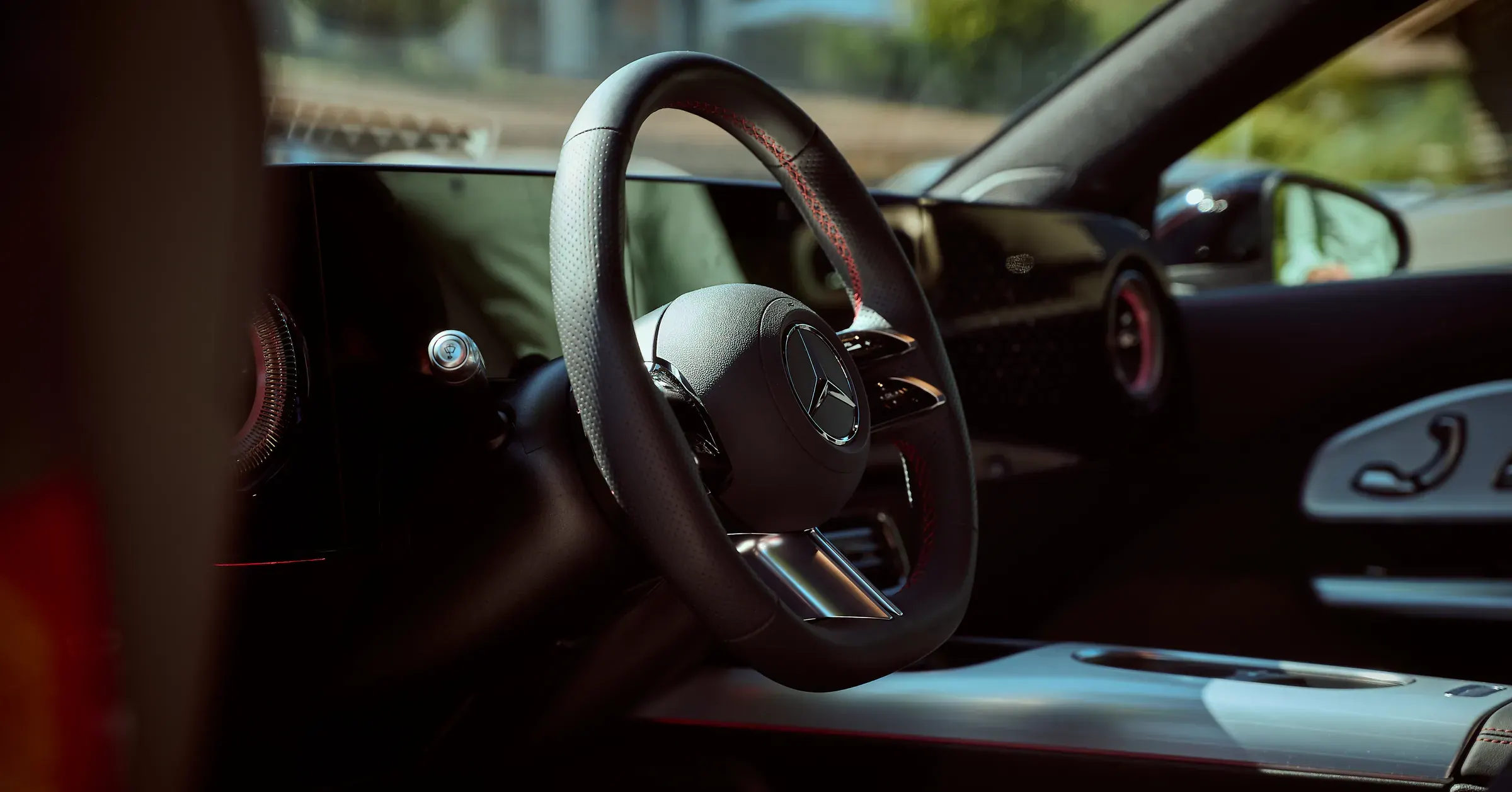 Volant Mercedes-Benz en cuir perforé à surpiqûres rouges, intérieur en lumière douce, photographe automobile à Giez
